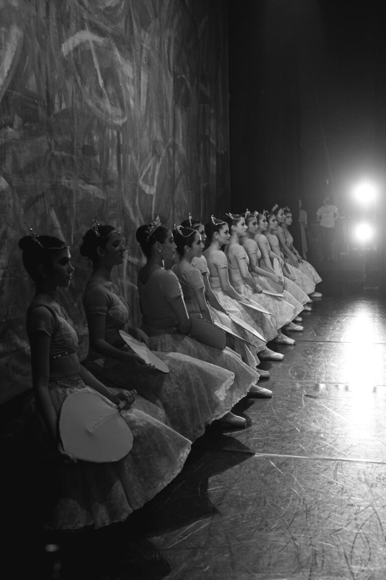 Black and white image of ballet dancers backstage preparing for a performance.
