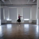 Elegant ballerina practicing a graceful ballet pose in a minimalist indoor studio.