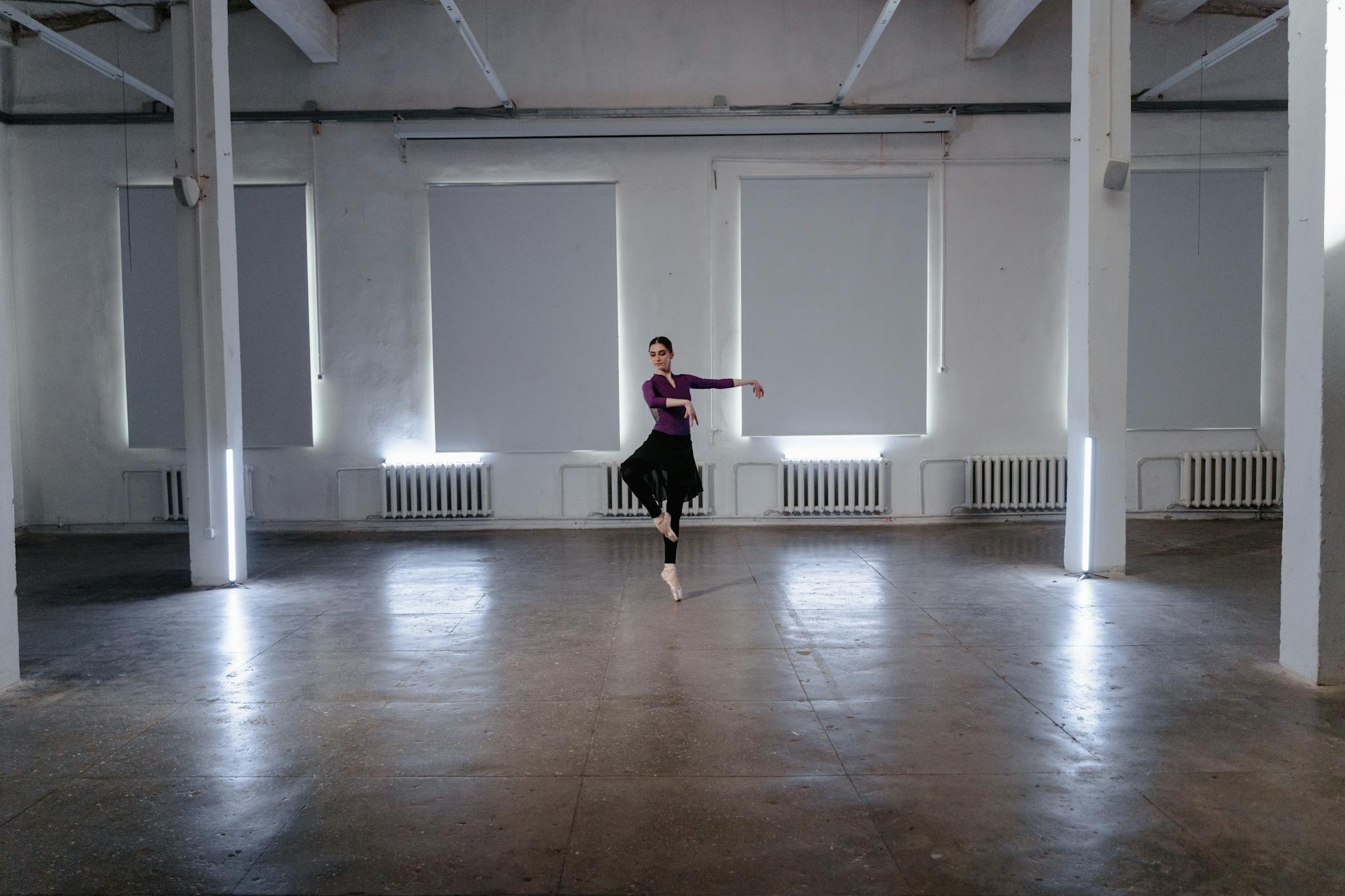 Elegant ballerina practicing a graceful ballet pose in a minimalist indoor studio.